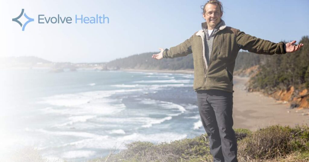 A man standing with a body of water in the background after a ketamine for anxiety treatment near portland